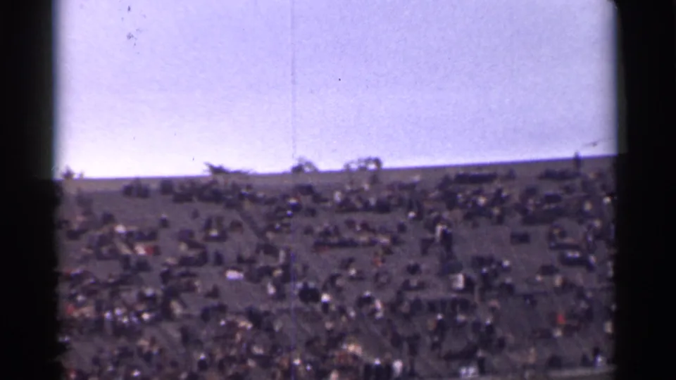 1944 San Francisco stadium crowd with a bird crossing the sky above the stands and goalpost in faded 8mm color.