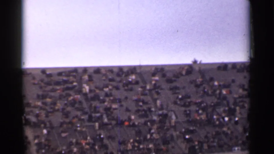 Wide 8mm view of a crowded San Francisco hillside, with many small figures seated or standing across the lawn.
