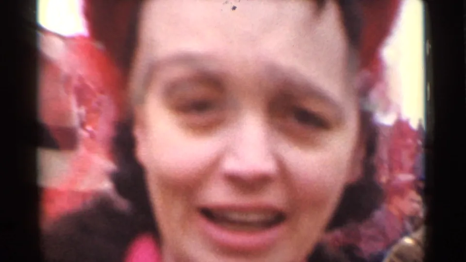 Close-up from the 1944 San Francisco home movie of a woman in a red hat or head covering looking toward the camera.