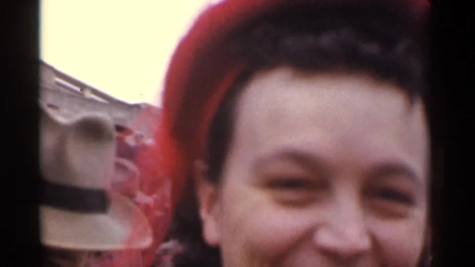 Close-up in the 1944 San Francisco footage of the smiling woman framed beside another spectator's hat and blurred background forms.