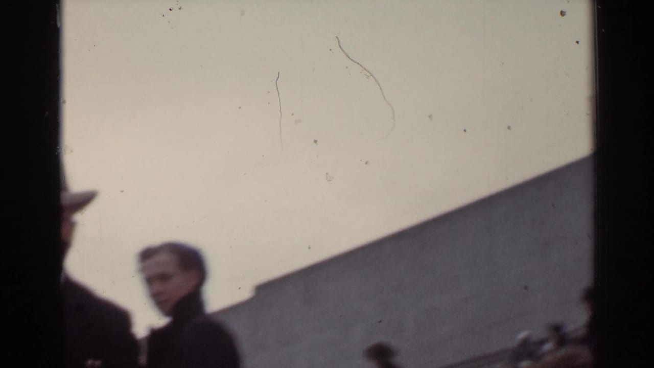 People near a stadium entrance or seating area, with a man partly visible at the left edge.