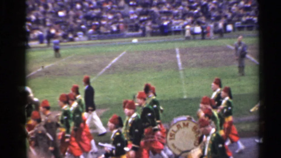 1944 San Francisco stadium footage showing a marching band with drums and brass moving along the sideline before a large crowd.