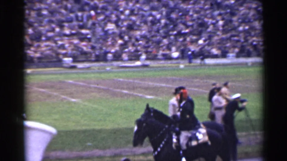 1944 San Francisco stadium frame showing a mounted rider near the football field edge as the crowd watches from the stands.