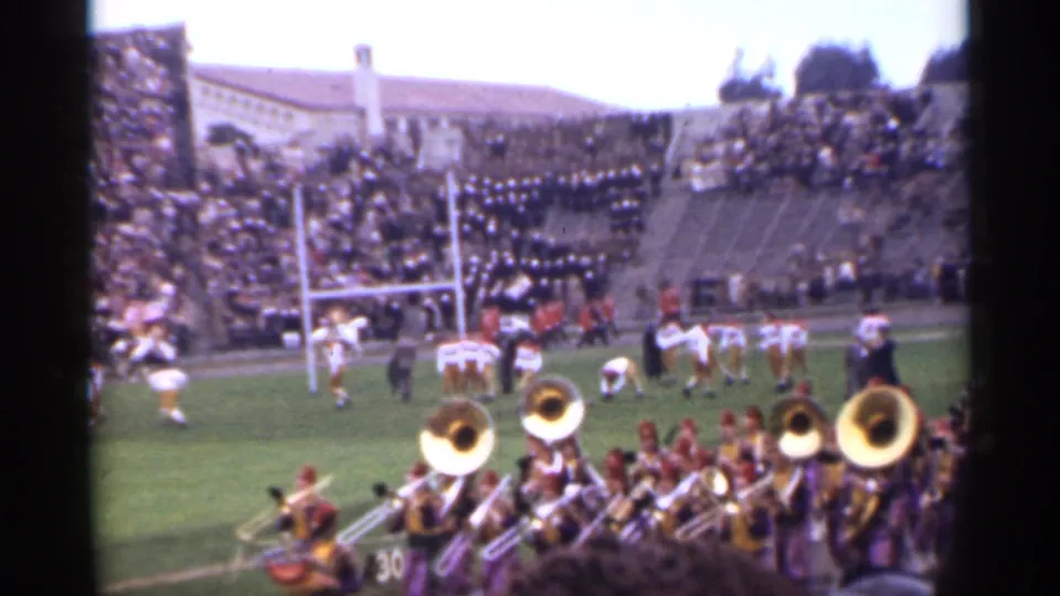 Spectator-shot 1944 San Francisco football scene with brass musicians in the foreground, players near the goal line, and a full stadium behind them.