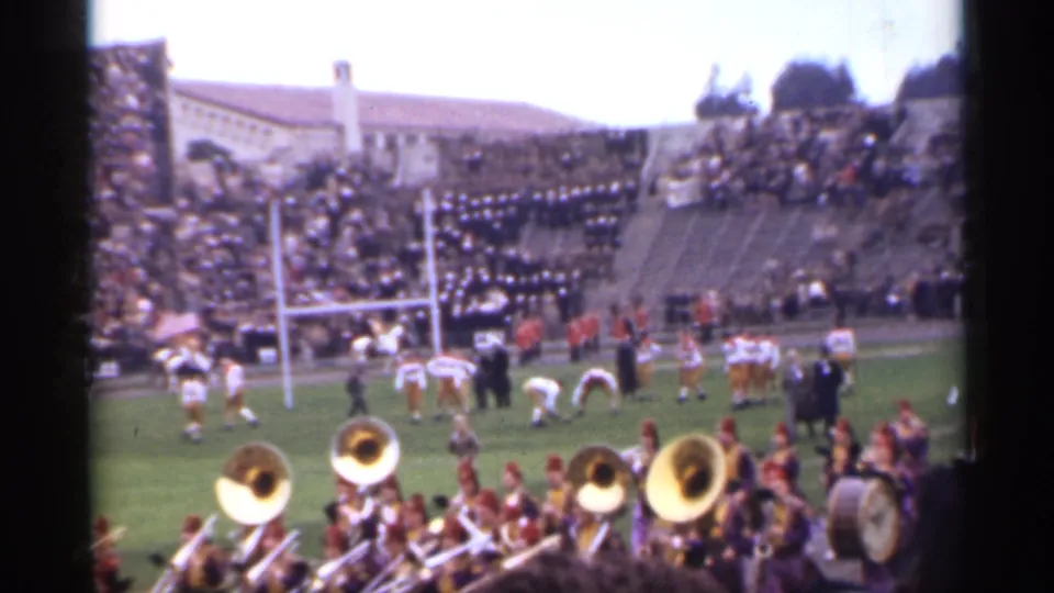 Color 8mm stadium view from San Francisco in 1944, with football players setting up near the goalposts and marching band musicians below the camera.