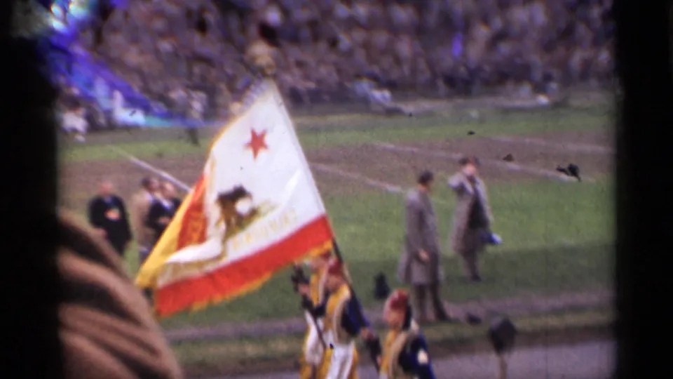 San Francisco 1944 stadium ceremony with a California state flag moving across the field during a football event.