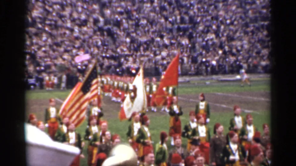 1944 San Francisco home-movie view of a band formation with flags and uniformed marchers on a football field.
