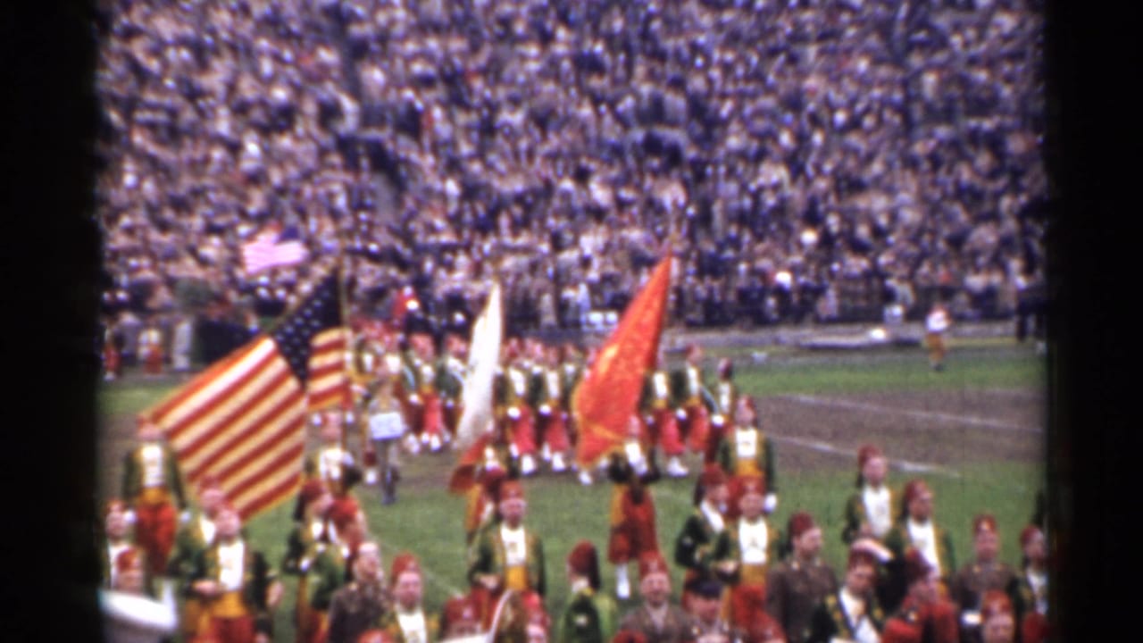 1944 San Francisco home-movie frame showing uniformed marchers, color guard flags, and packed stadium bleachers.
