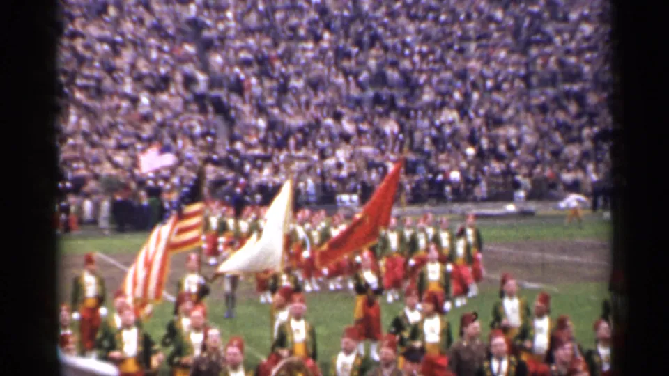 1944 San Francisco stadium footage with color guard flags and marching performers crossing the field before spectators.
