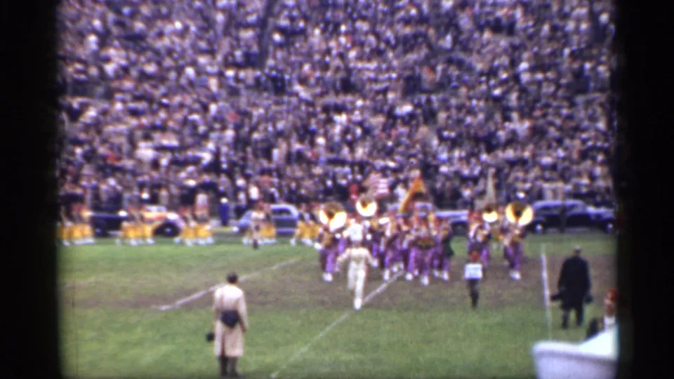 San Francisco 1944 halftime frame with purple-and-gold band uniforms, brass instruments and a crowded football stadium backdrop.