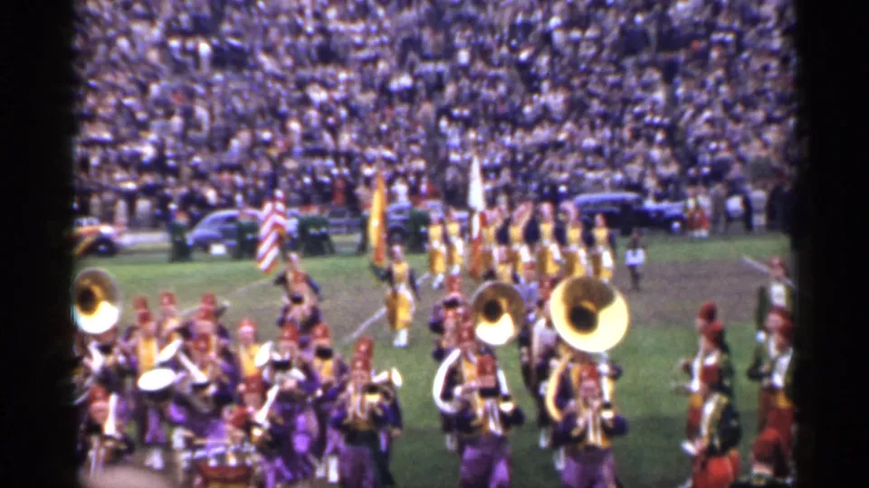 1944 San Francisco home-movie frame with brass players in front and flag bearers forming lines behind them.
