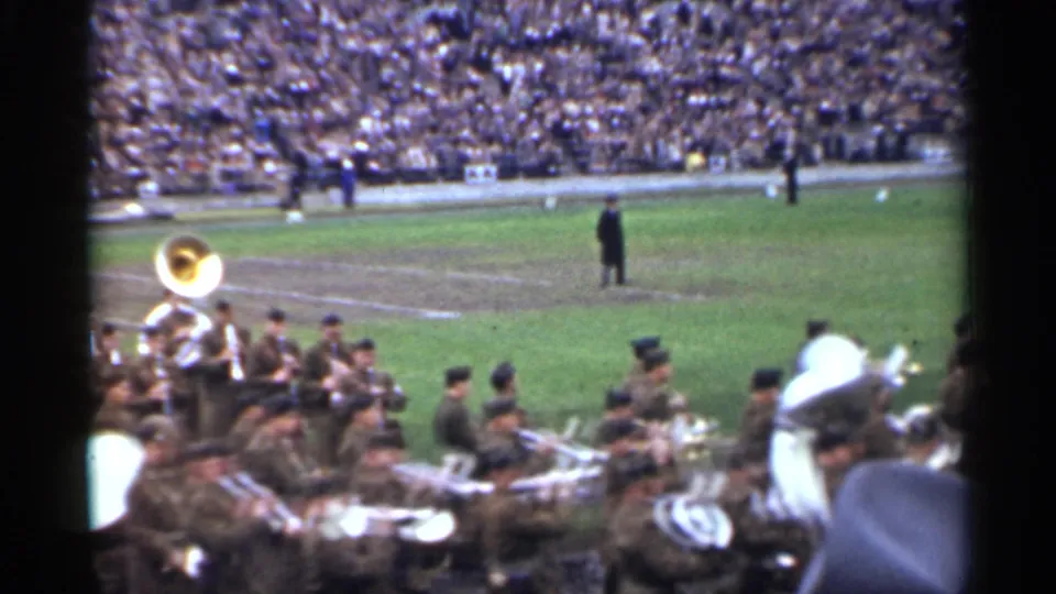 A 1944 San Francisco home-movie frame shows a military band with sousaphones and brass instruments beside the field.