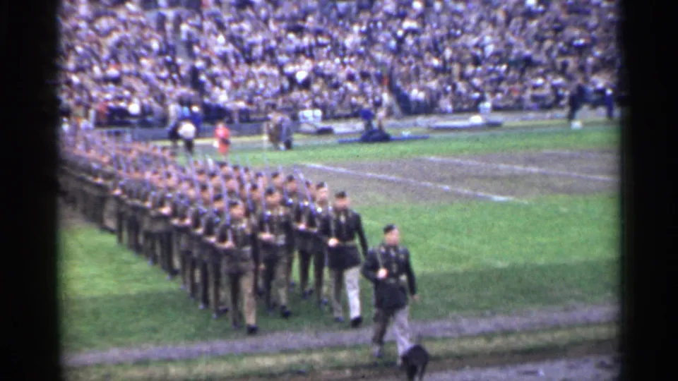 1944 San Francisco stadium footage shows uniformed soldiers marching in formation with a large crowd watching from the stands.