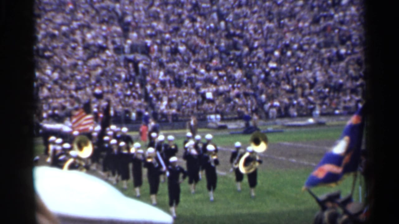 A 1944 San Francisco stadium view shows uniformed musicians carrying brass instruments and flags while marching across the field.