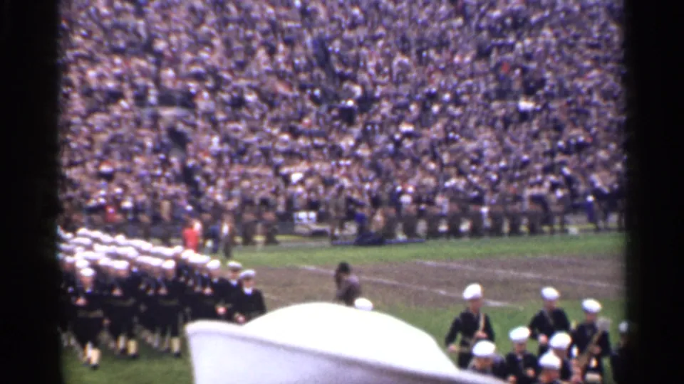 1944 San Francisco home-movie frame with a uniformed band moving onto a field before a large seated crowd.