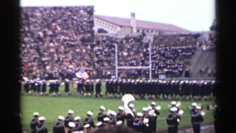 1944 San Francisco stadium frame showing an American flag, band members, goalposts, and a dense crowd in the bleachers.