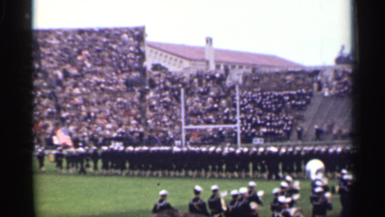 1944 San Francisco stadium view with a marching band crossing the field, an American flag, and dense bleachers in the background.