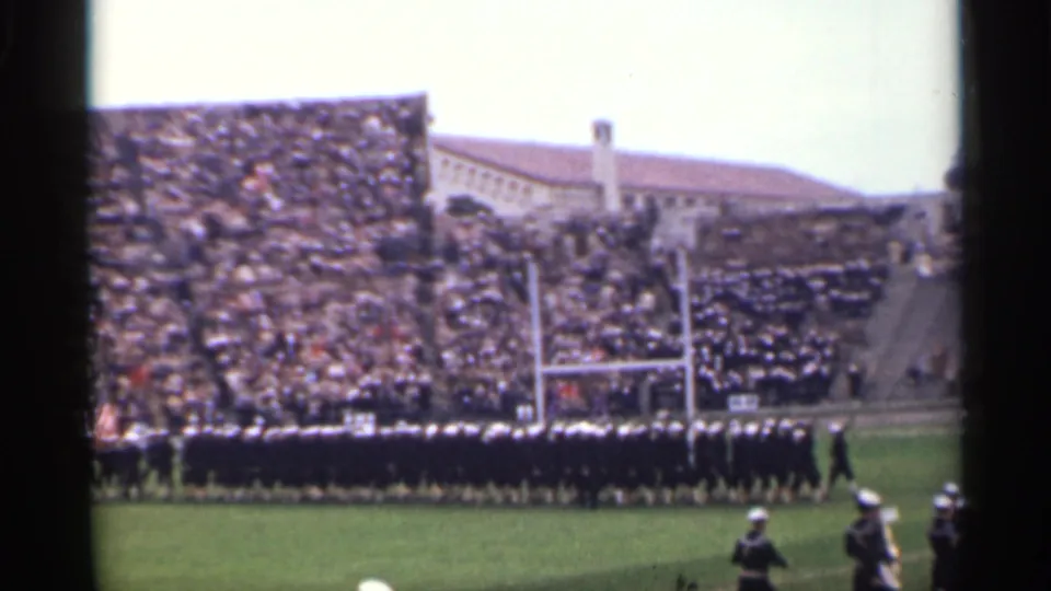 1944 San Francisco frame showing the marching band held in formation near football goal posts with a full stadium crowd behind.