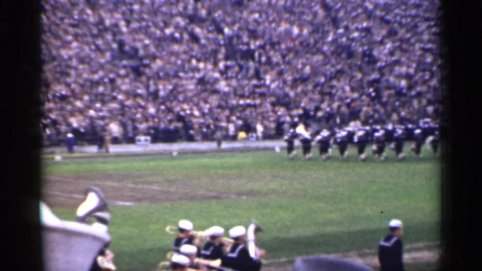 1944 San Francisco home-movie frame showing uniformed band members marching across a stadium field before a large crowd.