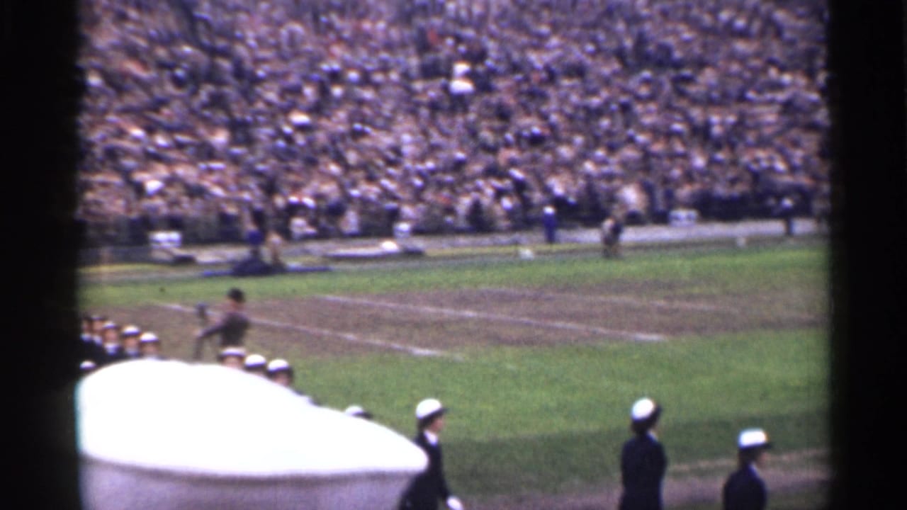 1944 San Francisco stadium view with uniformed marchers on a field, packed stands, and a large white foreground obstruction.