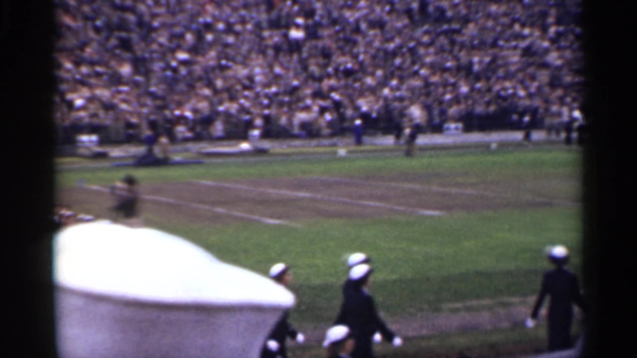 Uniformed marchers cross a San Francisco stadium field in 1944, seen from a spectator angle with bleachers in the background.