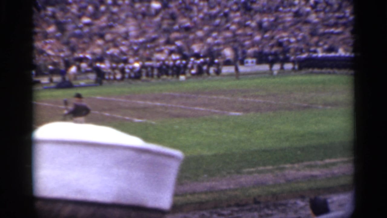 1944 San Francisco home-movie view of a football field, distant uniformed groups, and packed grandstands partly blocked by a sailor's cap.