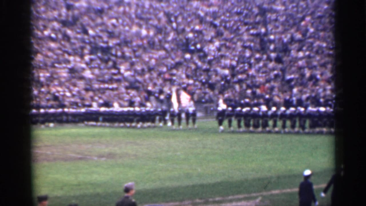 1944 San Francisco home-movie frame showing rows of uniformed personnel, flags near the field center, and packed stadium seating.