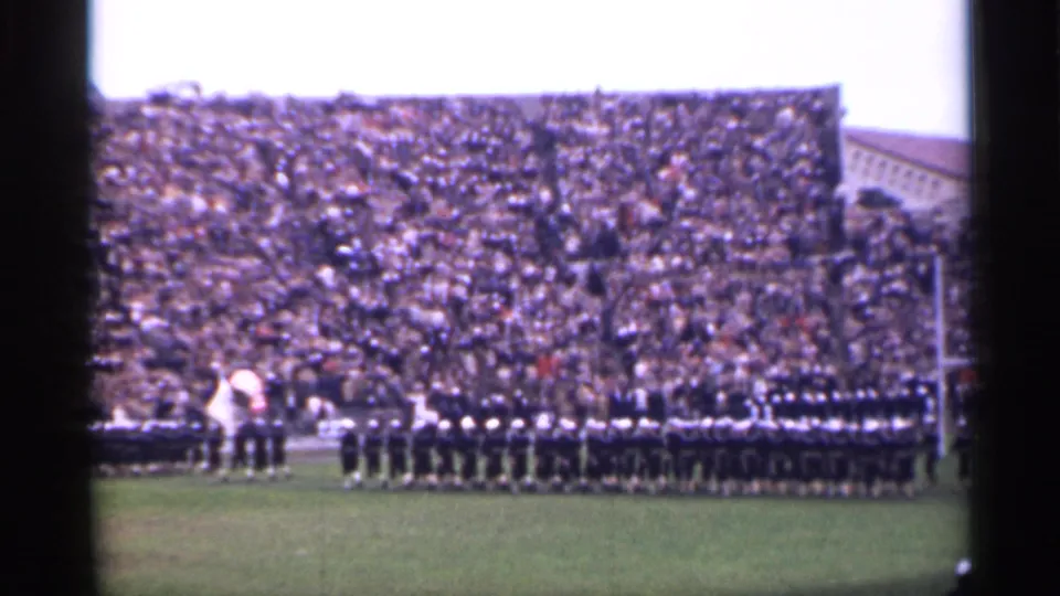 1944 San Francisco home-movie frame showing soldiers in formation on a stadium field with a dense crowd in the stands.