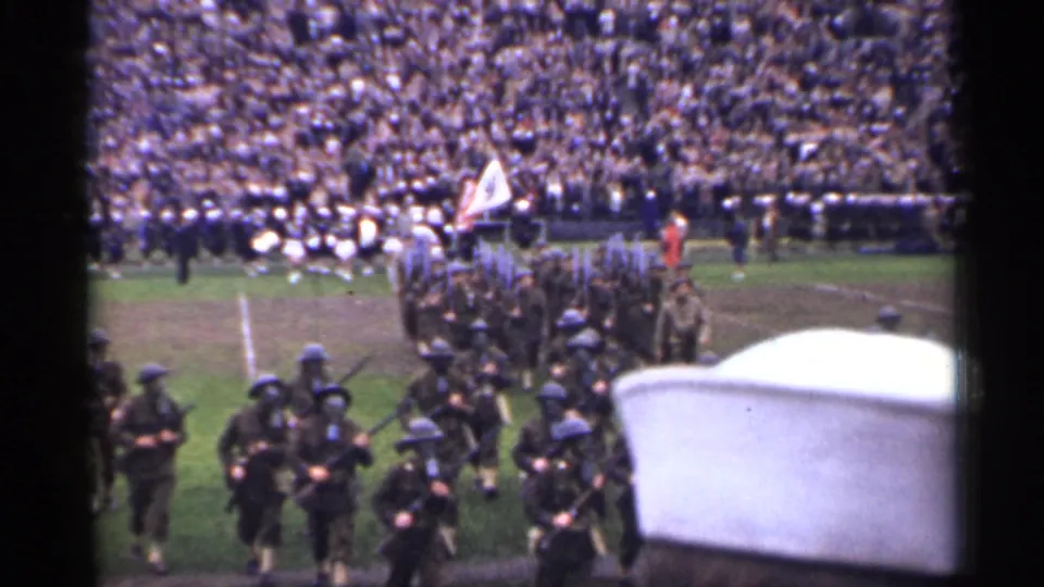 Home-movie view of soldiers with rifles marching nearer to the camera during a 1944 San Francisco athletic-field display.