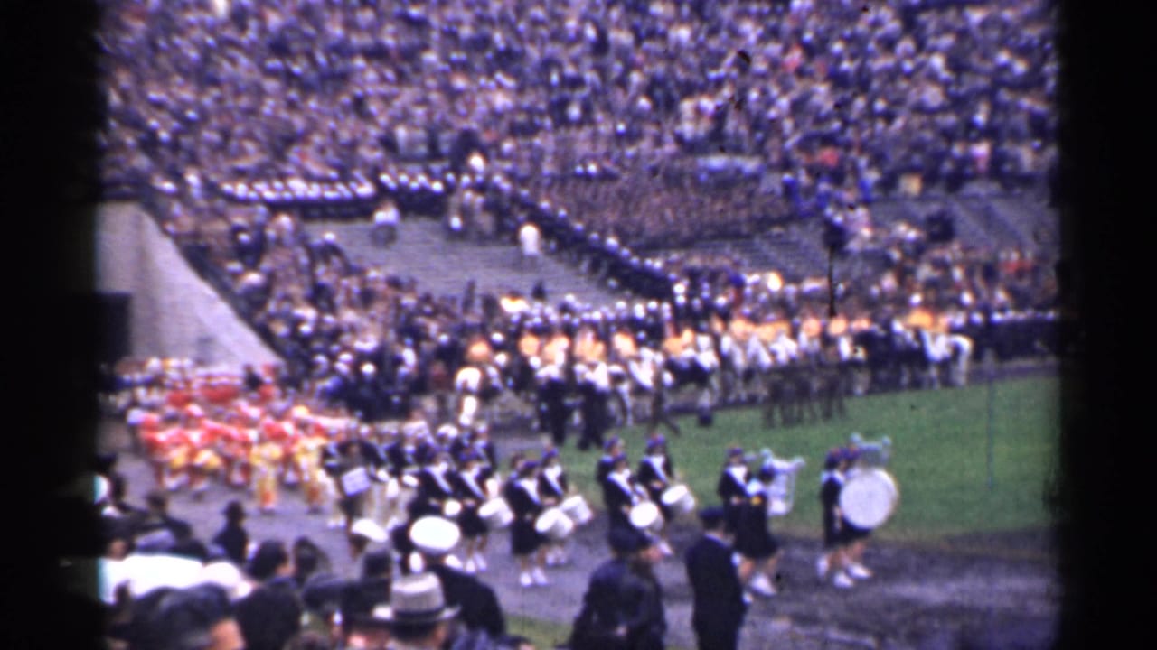 Wide 1944 San Francisco stadium view with marching groups, drummers, and spectators around a football field.