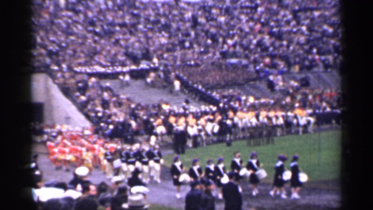 1944 San Francisco stadium footage shows uniformed performers on a green field with packed bleachers behind them.