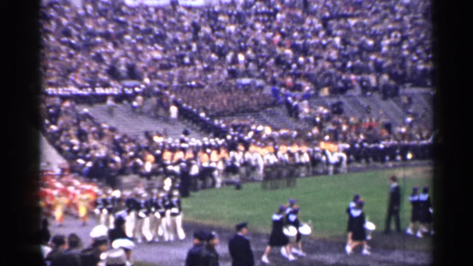 Uniformed musicians and performers move across the field in a 1944 San Francisco stadium home-movie shot.