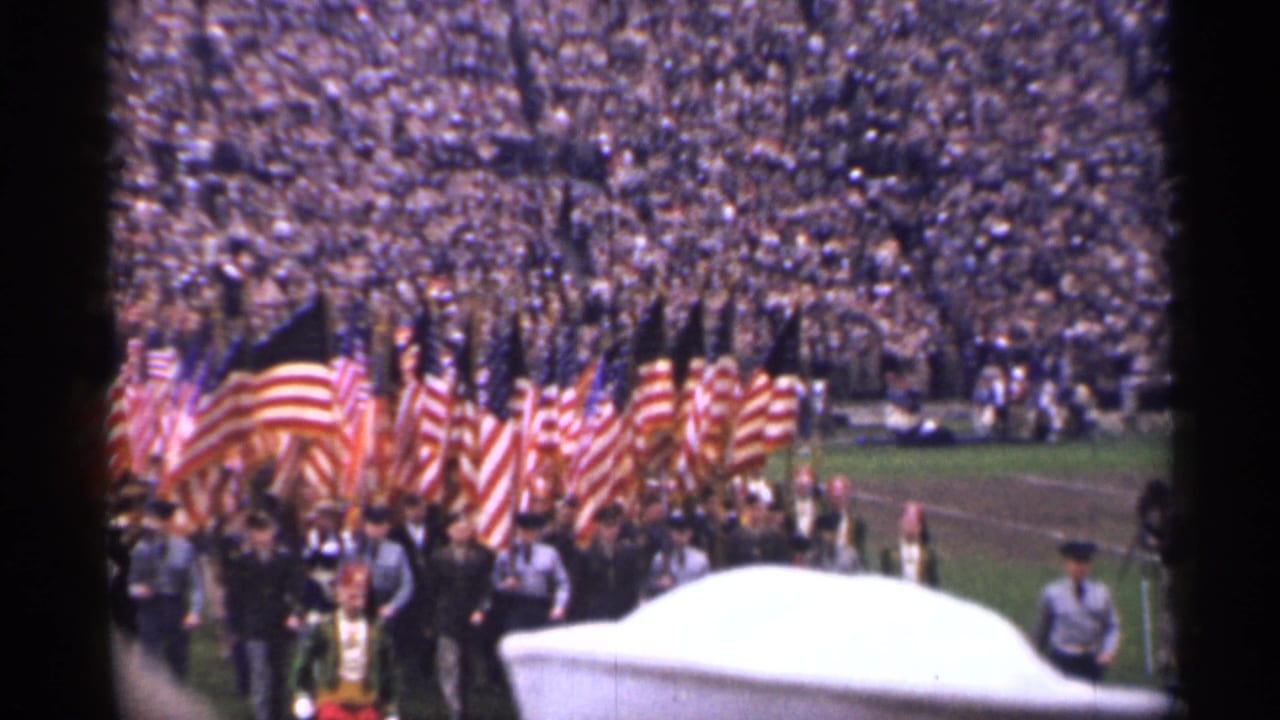 San Francisco 1944 stadium parade view with American flags, uniformed men, spectators, and a white foreground obstruction.