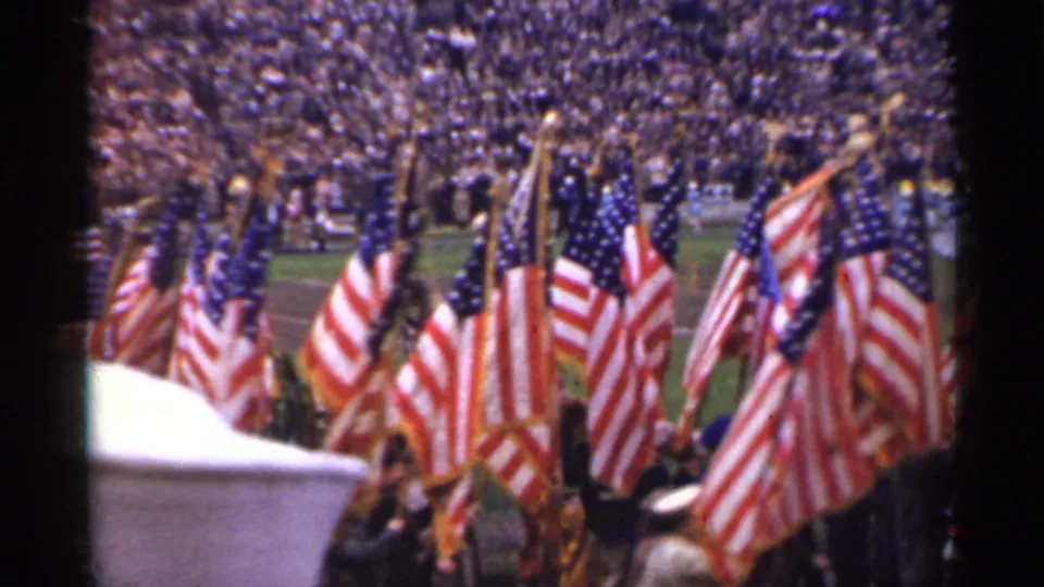 The closing frame shows massed American flags and uniformed figures passing before a large San Francisco stadium audience in 8mm color footage.