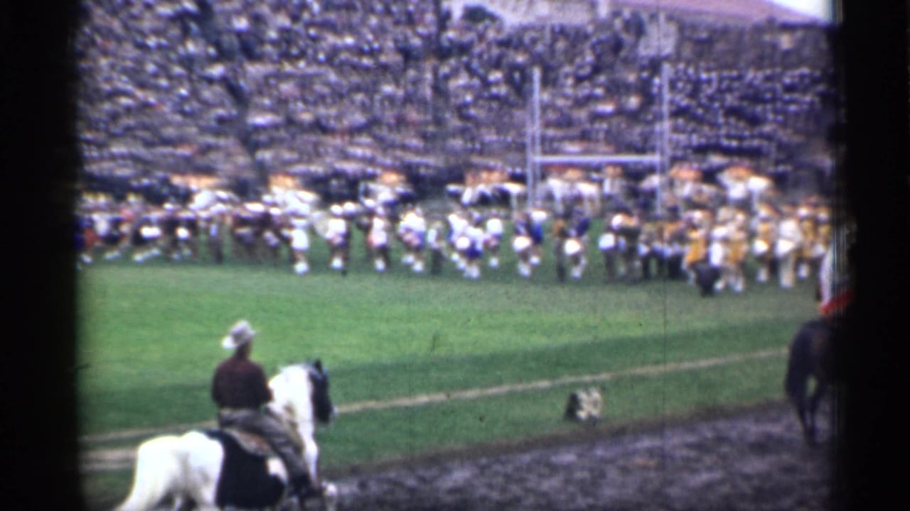 A 1944 San Francisco stadium field view shows a marching band formation, goal posts, spectators, and a rider on a white horse near the sideline.