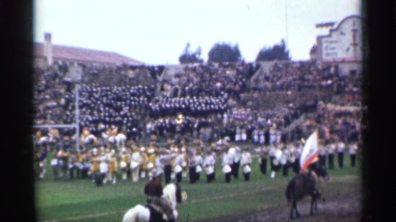 A flag-bearing horseback rider moves along the field during a 1944 San Francisco stadium band performance, with spectators filling the stands.