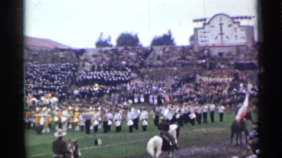 1944 San Francisco stadium scene with packed stands, a marching band on the field, a scoreboard structure, and mounted riders near the camera.