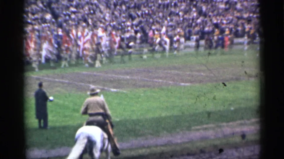 From the stands, a rider on a white horse faces the field while performers move near the far side of a crowded San Francisco stadium.