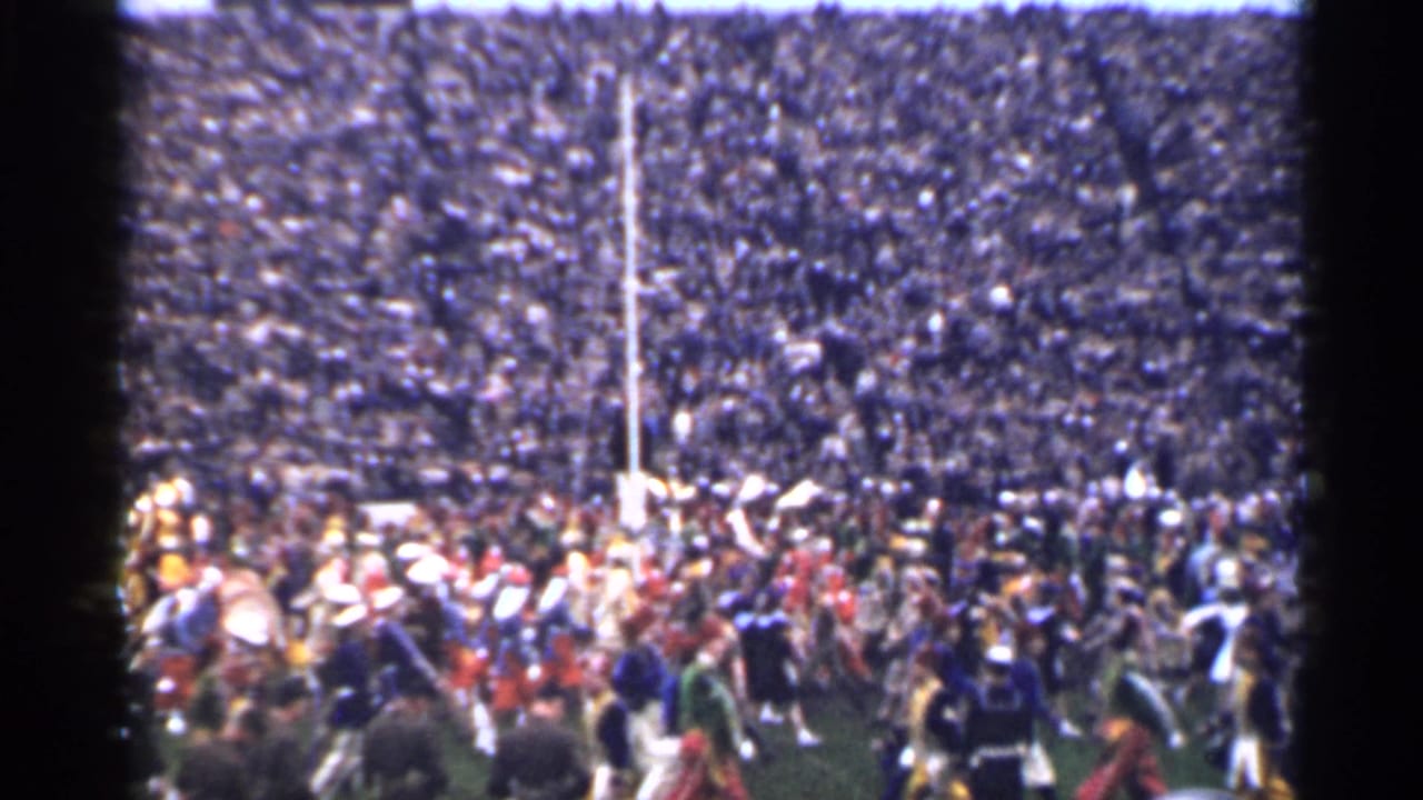 1944 San Francisco stadium scene with band members, spectators, and a white goalpost visible in soft 8mm color.