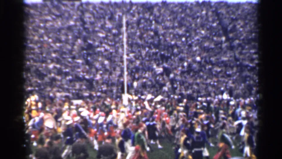 1944 San Francisco stadium scene with band members, spectators, and a white goalpost visible in soft 8mm color.