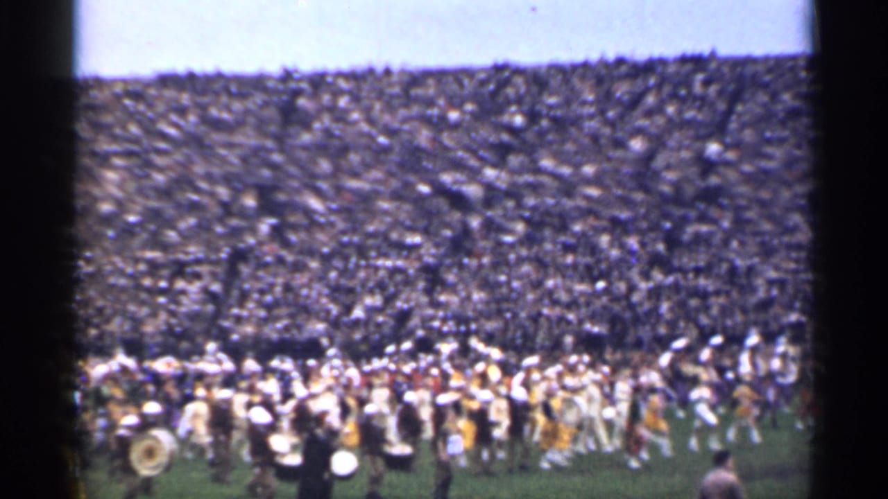 Home-movie view of a uniformed marching band performing on a stadium field in San Francisco, with a crowded audience in the stands.