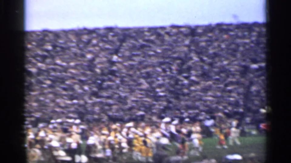 1944 San Francisco home-movie frame showing packed stadium seating and a marching band at field level.