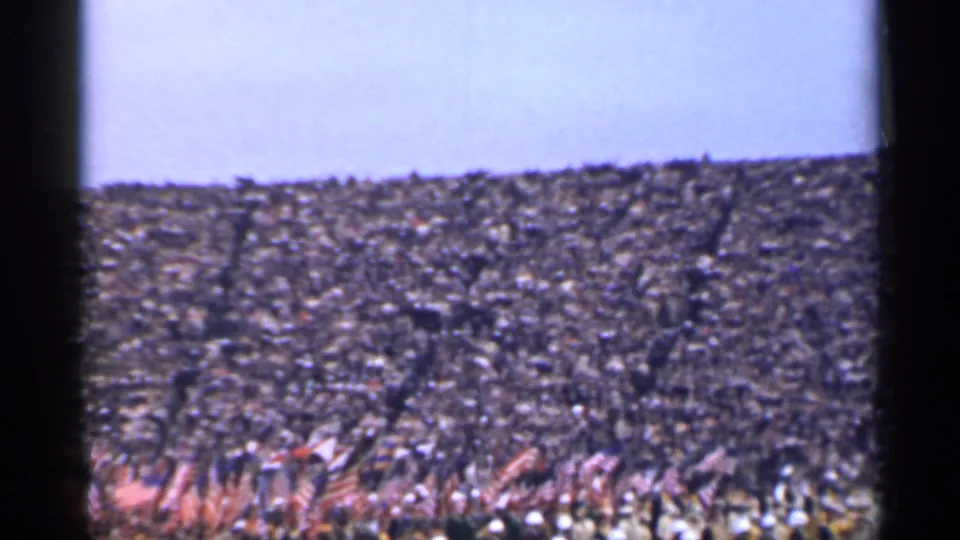 Distant 1944 San Francisco view of a dense outdoor crowd holding many American flags under a pale sky.