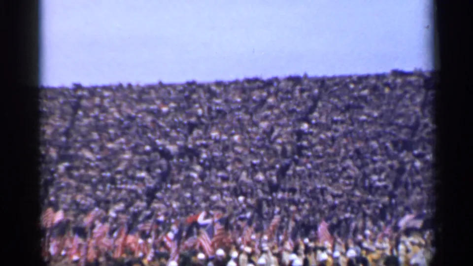 Wide 1944 San Francisco home-movie view of a patriotic crowd, with flags visible across the lower foreground.
