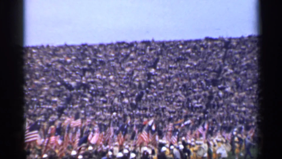 A wide 8mm view of a crowded San Francisco patriotic gathering, with American flags clustered along the lower edge of the frame.