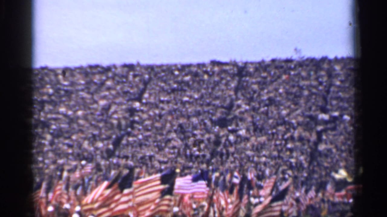 Distant view of a crowded San Francisco stadium in 1944, with American flags clustered at field level.