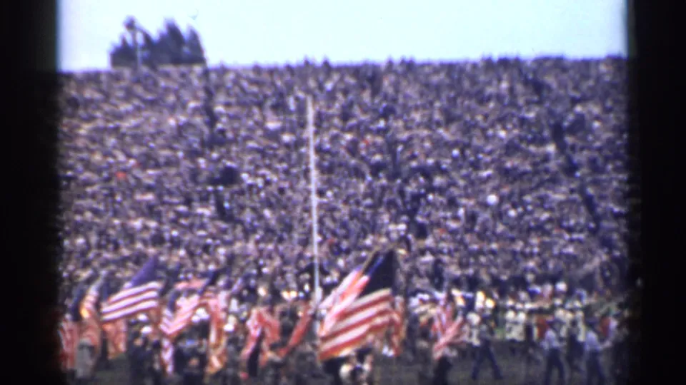 San Francisco 1944 stadium scene with American flags in front of uniformed ranks and a large crowd.