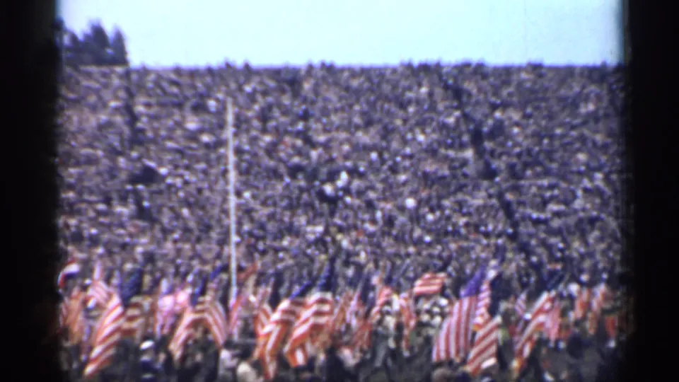 Final frame of the 1944 San Francisco home movie clip with flags in front of a large stadium audience.