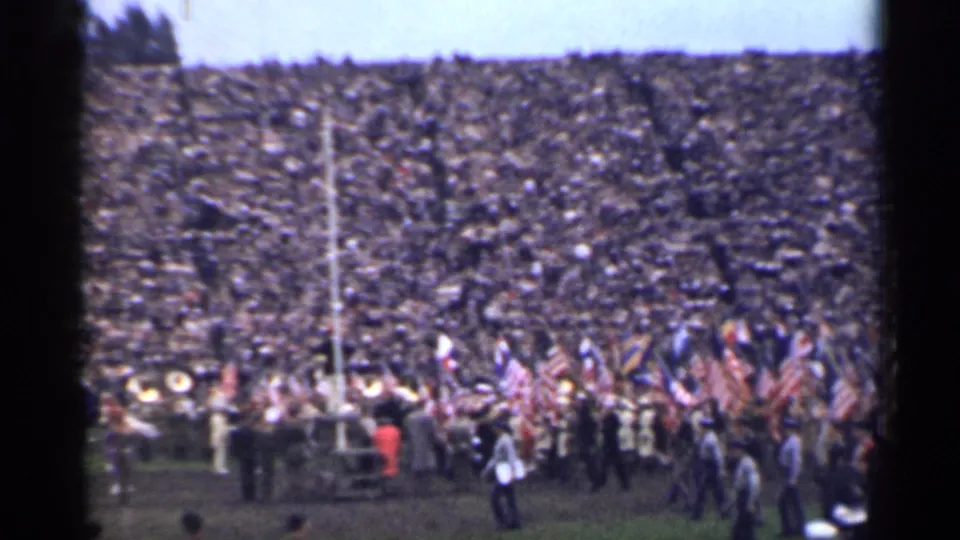1944 San Francisco stadium view with people walking at field level and flags below packed bleachers.