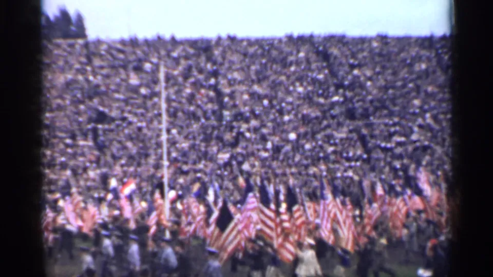 Home-movie view of a packed San Francisco stadium with flag bearers marching below the stands in 1944.
